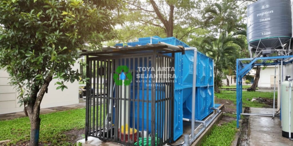 Instalasi sistem IPAL MBG modular profesional berwarna biru oleh Toya Arta Sejahtera, lengkap dengan pengaman pagar besi dan tangki penampungan.