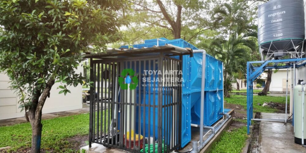 Instalasi sistem IPAL MBG modular profesional berwarna biru oleh Toya Arta Sejahtera, lengkap dengan pengaman pagar besi dan tangki penampungan.