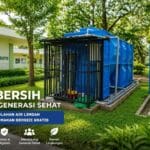 Sistem Instalasi Pengolahan Air Limbah (IPAL MBG) buatan Toya Arta Sejahtera, dipasang di area terbuka hijau samping gedung Dapur Makan Bergizi Gratis. Menampilkan tangki modular biru, unit filtrasi dalam kerangka besi, dan tangki penampung air olahan.